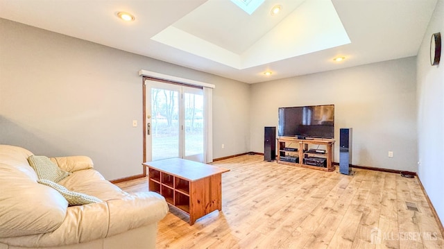 living room with a skylight, light wood-style flooring, and baseboards