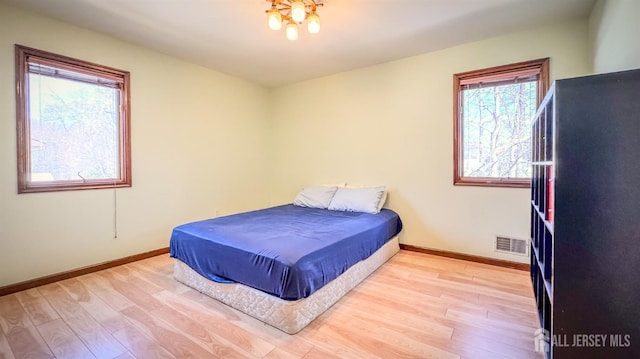 bedroom with baseboards, visible vents, and wood finished floors