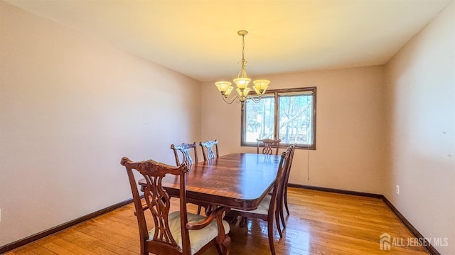 dining space featuring light wood-style flooring, baseboards, and a chandelier