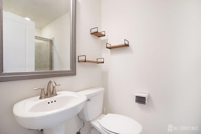 bathroom with a stall shower, a sink, and toilet