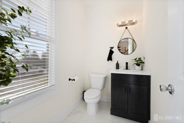 half bath with baseboards, vanity, and toilet