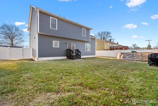 rear view of property featuring entry steps, a yard, a fenced backyard, and a gate