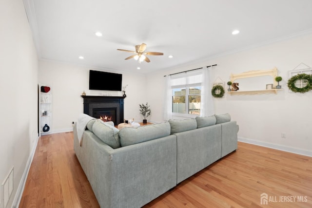 living room with crown molding, a lit fireplace, and wood finished floors