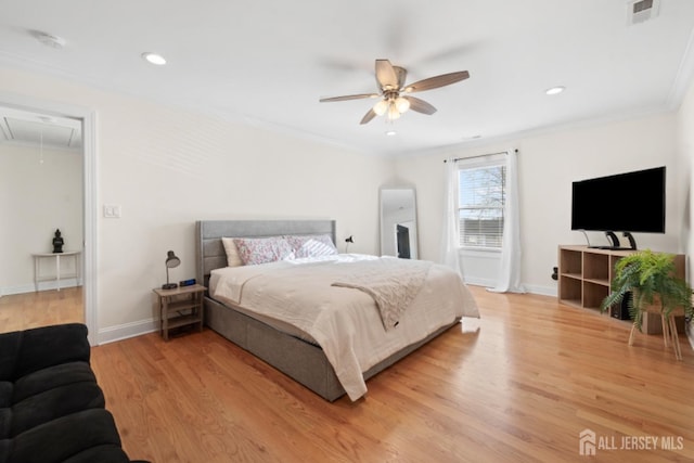 bedroom with crown molding, visible vents, attic access, light wood-type flooring, and baseboards