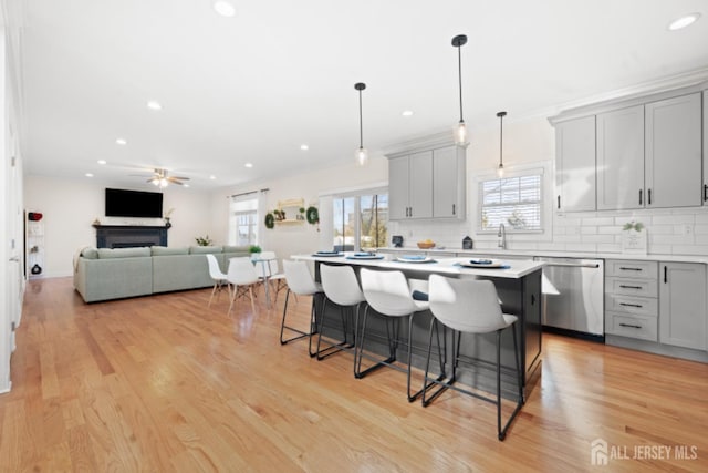 kitchen featuring a breakfast bar, dishwasher, backsplash, and gray cabinetry