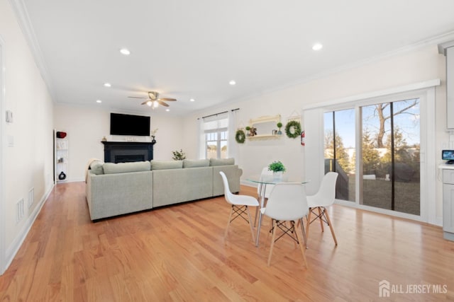 dining space featuring recessed lighting, a fireplace, visible vents, light wood finished floors, and crown molding