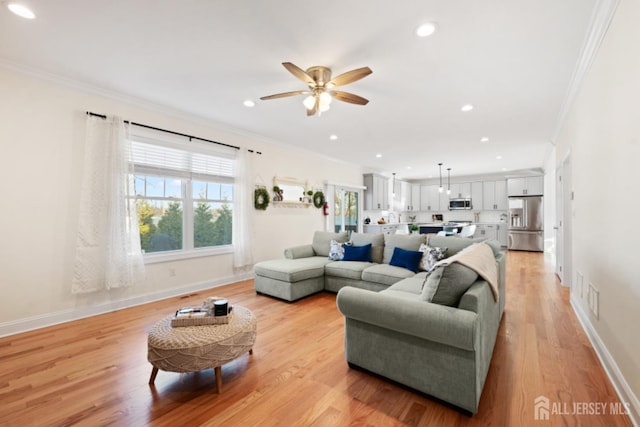 living room featuring ornamental molding, light wood-type flooring, baseboards, and recessed lighting