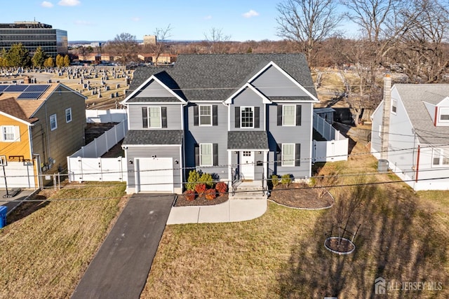 traditional-style home with aphalt driveway, a shingled roof, fence, a gate, and a front lawn