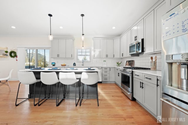 kitchen featuring appliances with stainless steel finishes, light countertops, a breakfast bar area, and tasteful backsplash