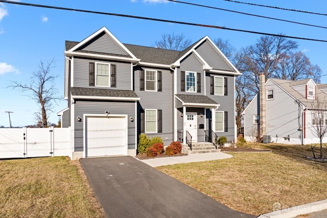 traditional home featuring aphalt driveway, roof with shingles, a gate, fence, and a front lawn