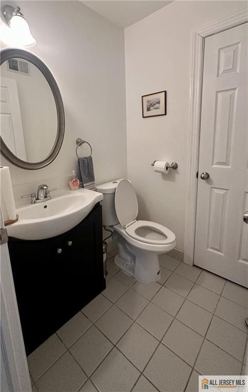 half bathroom with toilet, tile patterned floors, visible vents, and vanity