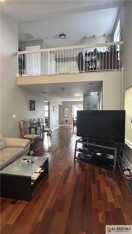 living area with baseboards, wood finished floors, and a towering ceiling
