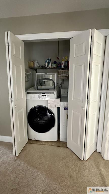 laundry area with laundry area, washer and dryer, and light colored carpet