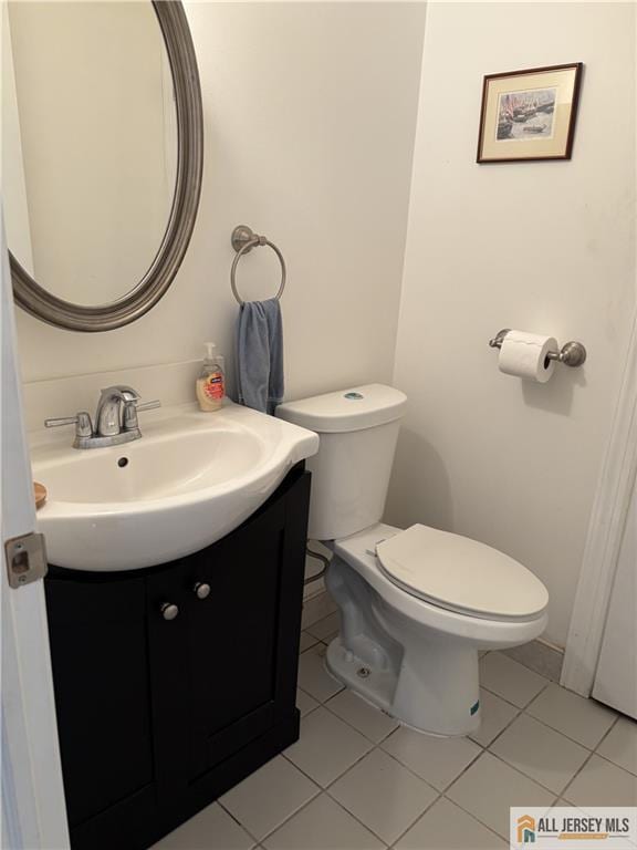 half bathroom featuring tile patterned floors, toilet, and vanity