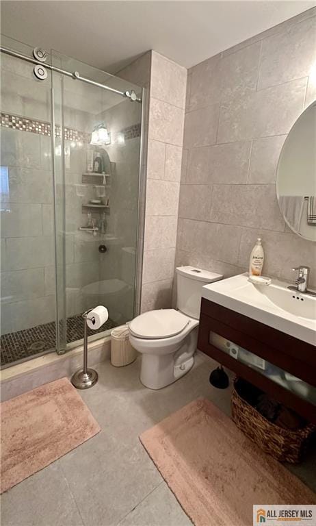 bathroom featuring tile walls, a shower stall, vanity, tile patterned floors, and toilet