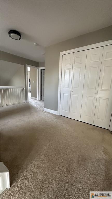 unfurnished bedroom with carpet floors, baseboards, and a closet