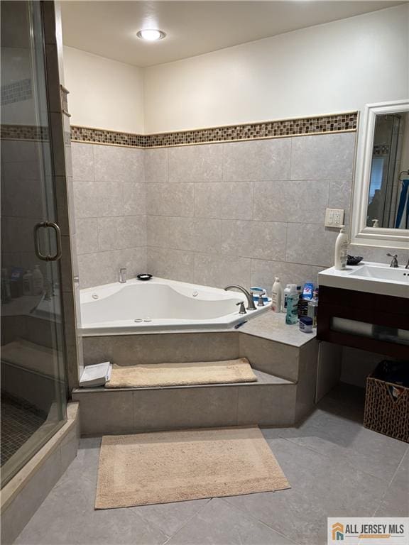 full bathroom featuring tile patterned flooring, tile walls, a stall shower, a bath, and vanity