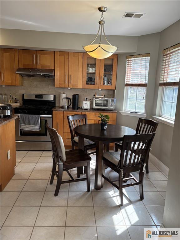 dining room with light tile patterned floors, visible vents, and a toaster