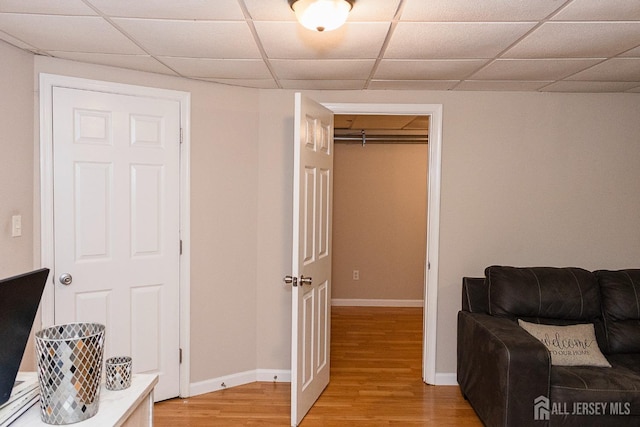 living area with light wood-style floors, baseboards, and a drop ceiling