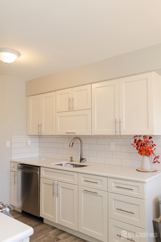 kitchen featuring stainless steel dishwasher, a sink, decorative backsplash, and white cabinetry