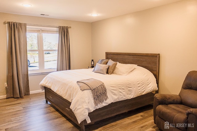 bedroom with wood finished floors, baseboards, and recessed lighting