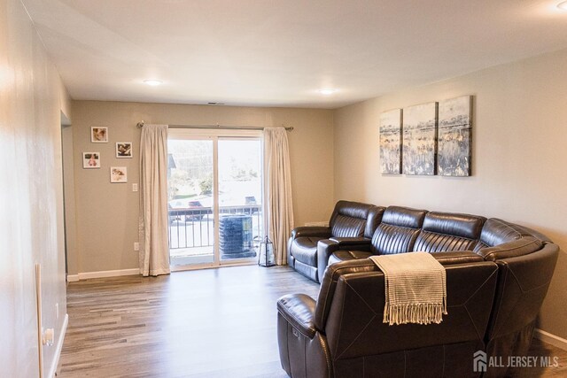 living room with wood finished floors, baseboards, and recessed lighting