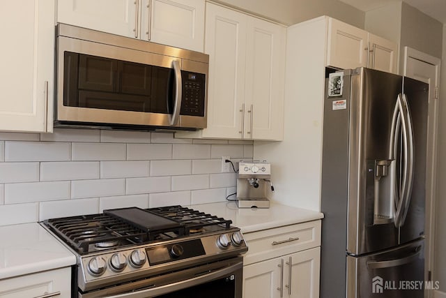 kitchen with appliances with stainless steel finishes, light countertops, decorative backsplash, and white cabinetry