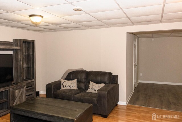 living room featuring light wood finished floors, baseboards, and a drop ceiling