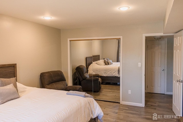 bedroom with a closet, wood finished floors, and baseboards