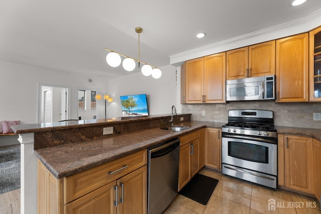 kitchen with a peninsula, a sink, appliances with stainless steel finishes, backsplash, and dark stone countertops