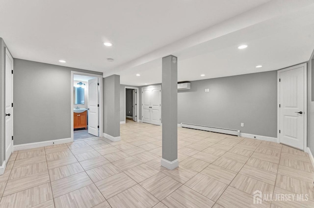 finished below grade area featuring a baseboard radiator, a wall mounted air conditioner, baseboards, and recessed lighting