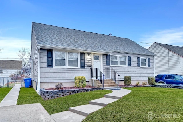 bungalow-style house featuring roof with shingles and a front lawn