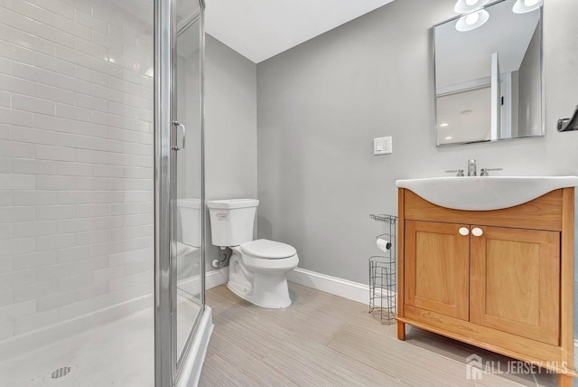 full bath featuring toilet, a shower stall, baseboards, and vanity