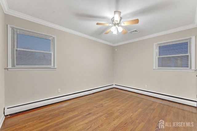 spare room featuring a ceiling fan, wood finished floors, visible vents, and crown molding