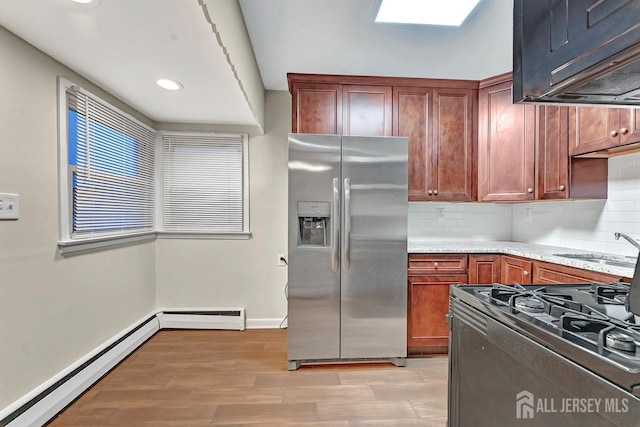 kitchen featuring stainless steel fridge, light stone counters, baseboard heating, and decorative backsplash