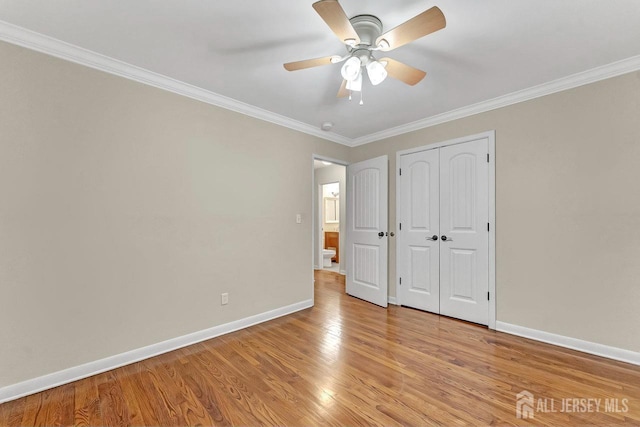 unfurnished bedroom with light wood-style flooring, a ceiling fan, baseboards, a closet, and crown molding