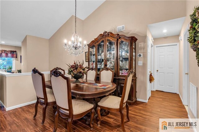 dining space featuring hardwood / wood-style flooring and an inviting chandelier