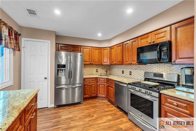 kitchen featuring light wood finished floors, visible vents, appliances with stainless steel finishes, and a sink