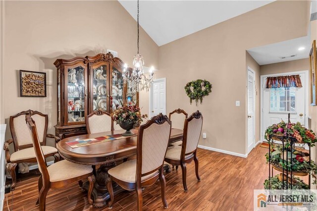 dining room featuring high vaulted ceiling, wood-type flooring, and a notable chandelier