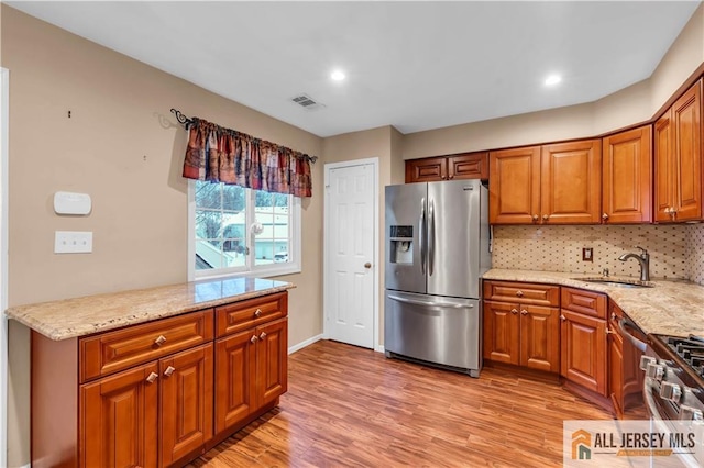 kitchen with light wood finished floors, stainless steel appliances, tasteful backsplash, visible vents, and a sink