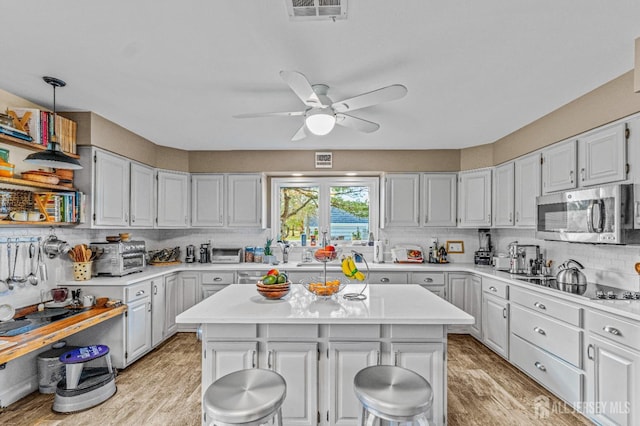 kitchen with white cabinetry, black electric stovetop, light wood-type flooring, and a kitchen island