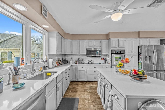 kitchen featuring sink, ceiling fan, appliances with stainless steel finishes, white cabinetry, and decorative backsplash