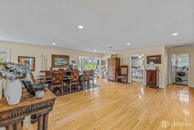 living room with washer / clothes dryer and light hardwood / wood-style flooring