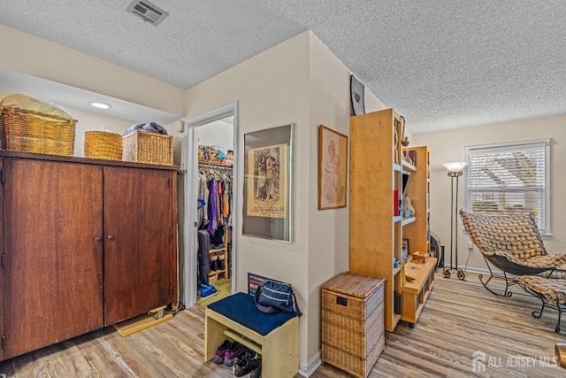 hall featuring a textured ceiling and light wood-type flooring