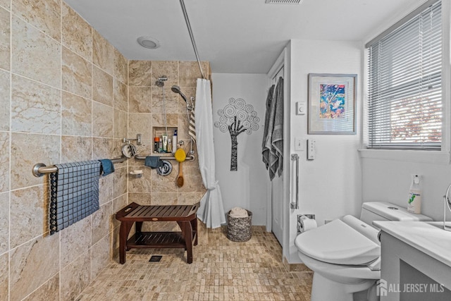 bathroom with tiled shower and toilet