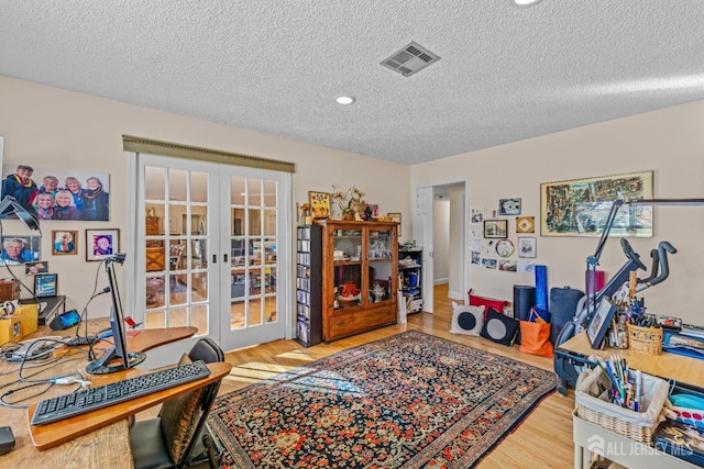 office with light hardwood / wood-style floors, french doors, and a textured ceiling