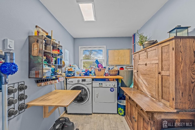 laundry area with washing machine and clothes dryer and light wood-type flooring