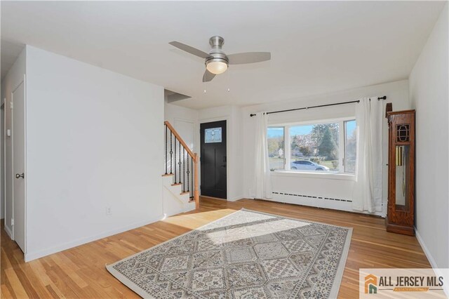 foyer entrance with a baseboard radiator, hardwood / wood-style floors, and ceiling fan