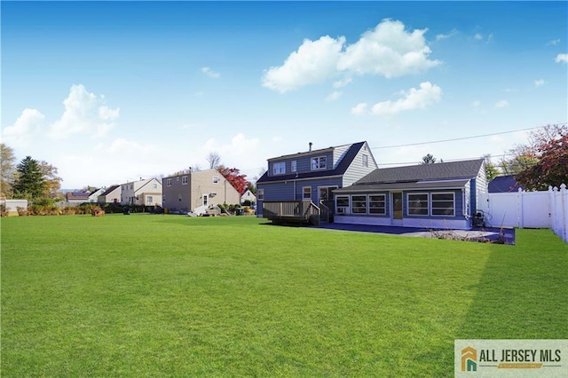 rear view of property with a wooden deck and a lawn