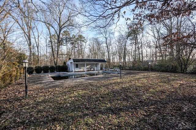view of yard with a storage structure, an outdoor structure, a view of trees, and a pool